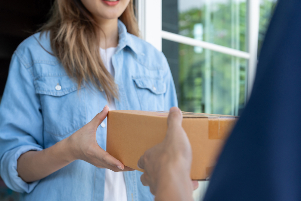 Woman being handed a package by a delivery person.