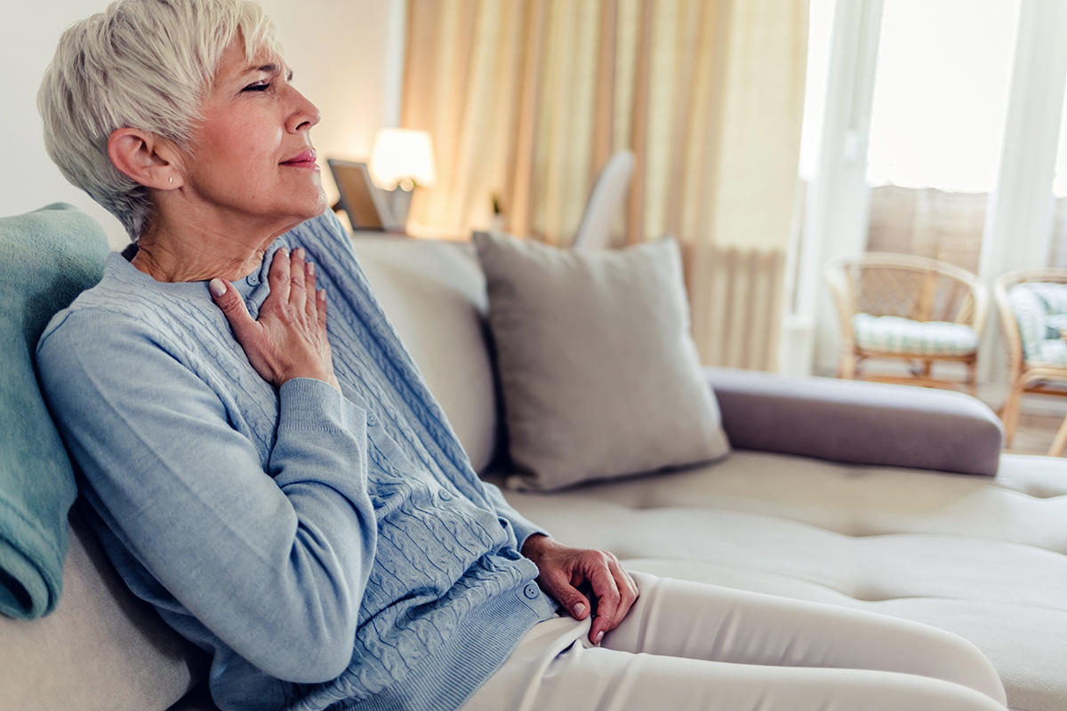  Older woman holding her hand over her chest in pain.